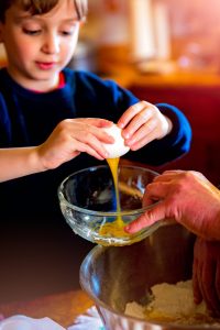 child cracking an egg into a bowl