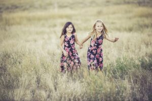 2 girls running through a field frugal fun