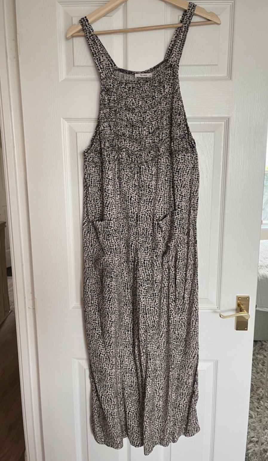Black jumpsuit on a hanger over a door