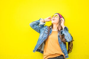 smiling woman looking up standing against yellow wall