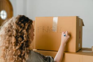 unrecognizable-woman-writing-note-on-carton-box-with-marker