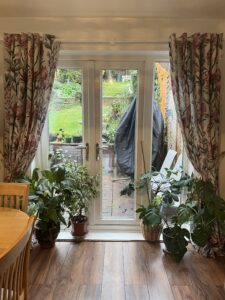 A dining room with patio doors framed by floral pink and green curtains