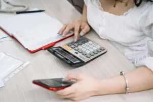 woman using a black and red smartphone and calculator