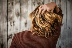 Back of a woman's head showing her running her fingers through her hair