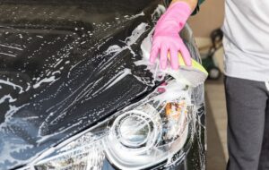 A hand washing a car bonnet