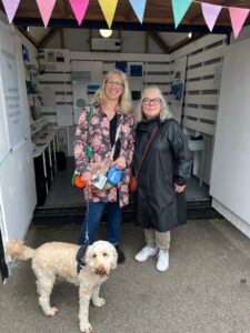 Two women in coats in a hut with a dog