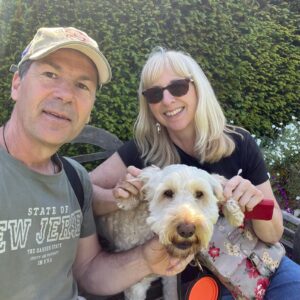 Man and women sitting with a cockapoo dog