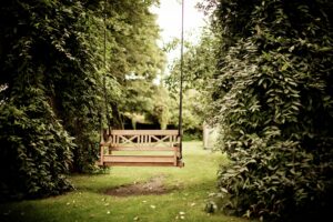 A hanging bench in a lush green garden