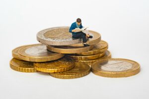 man sitting on a pile of giant coins