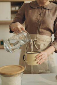 woman-in-apron-putting-pouring-water-in-cup