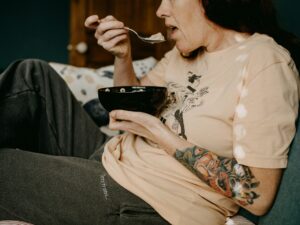 Woman eating a bowl of cereal on a sofa
