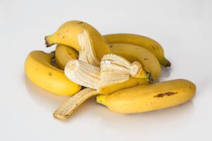 A small pile of bananas, one semi peeled