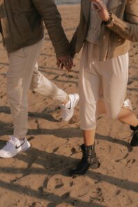 Man and woman walking on the beach wearing casual clothing
