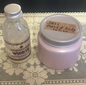 A glass bottle of Wide Eye cleaners and a plain purple plastic container