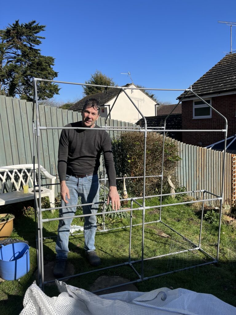 A man assembling a greenhouse frame - get back to the garden