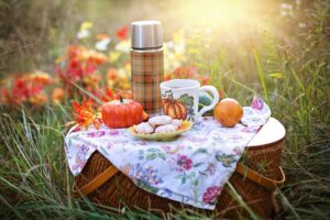 a small picnic table in a field of flowers with food and a flask