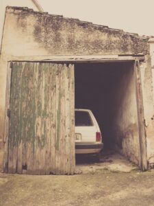 An old garage with one door open showing part of a car