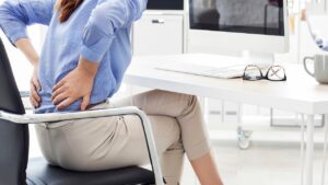 Woman sitting in a chair and holding her back