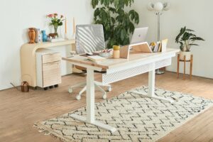 A white office desk in a neutral coloured room with plant