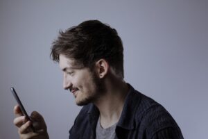 A young man looking at his phone screen and smiling