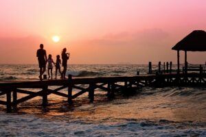 A family on a pier over looking the sea at sunset