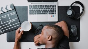 Man with his head on his desk and a laptop