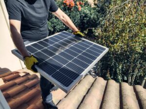 Man carrying a solar panel on a roof