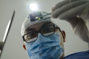A male dentish with mask head cover and bright light close up