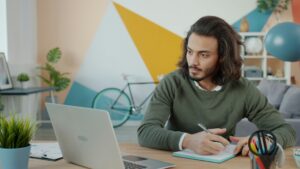 Man working at a desk with a laptop and notebook